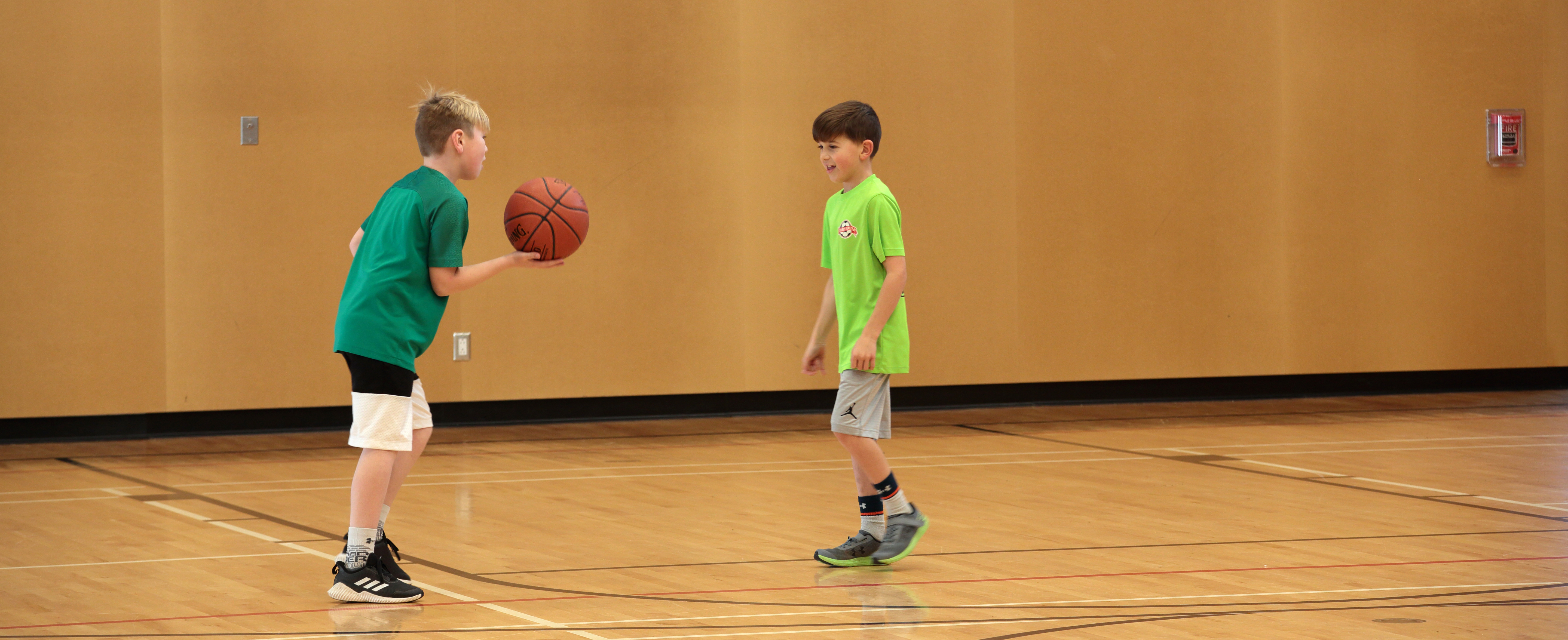 Two boys playing basketball in a gym